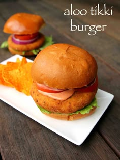 two burgers on a plate with potato chips and ketchup in the foreground