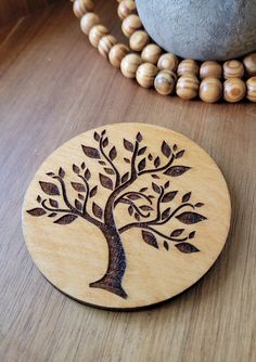 a wooden brooch with a tree on it next to a bead necklace holder