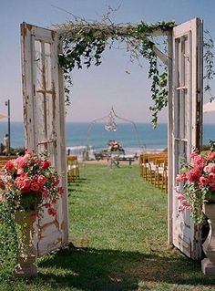 an outdoor ceremony set up with flowers and greenery on the grass near the ocean