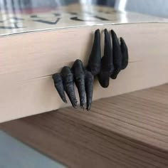 four black nails stuck in the side of a wooden shelf