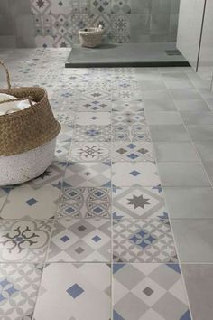 a bathroom with blue and white tiles on the floor, including a basket in the middle