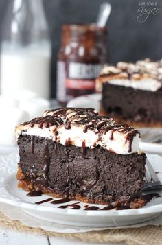 a slice of chocolate cake on a white plate with a fork and glass of milk in the background