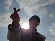 a young man is making the peace sign with his fingers while standing in front of the sun