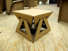 a cardboard box sitting on top of a wooden floor next to other boxes and chairs