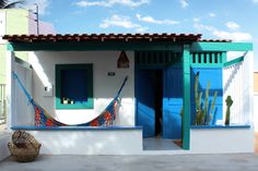 a small white house with blue doors and hammock hanging from the front porch