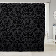 a black shower curtain with an ornate design on it's side in a bathroom