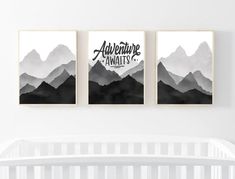 three black and white mountains are hanging on the wall above a crib in a nursery