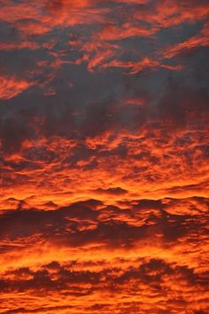 an orange and red sunset with clouds in the sky