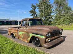 an old rusty truck is parked on the side of the road