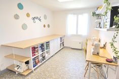 a sewing room with lots of craft supplies on the shelf and shelves in front of the window