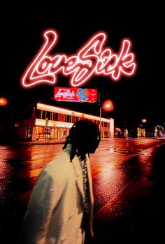 a man walking down the street in front of a neon sign