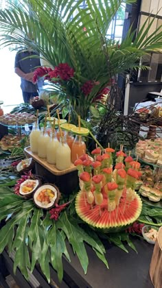 an assortment of fruits and snacks on a buffet table with palm trees in the background