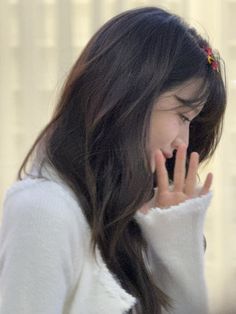 a woman talking on her cell phone while wearing a white sweater