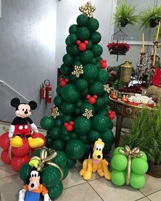 a christmas tree made out of balloons and mickey mouse figurines on the floor