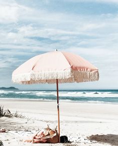 an umbrella is on the beach next to some towels and blankets in front of the ocean