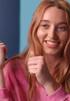 a woman is brushing her hair and smiling