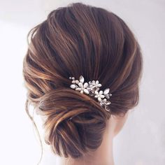 a woman wearing a bridal hair comb with flowers in it's back end