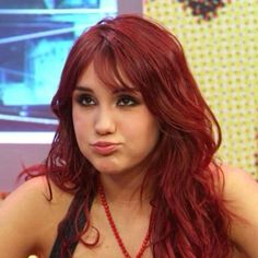 a woman with long red hair is posing for the camera and looking at the camera