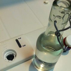 a glass bottle sitting on top of a counter next to a digital camera and an mp3 player