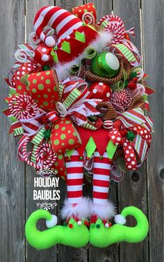 a christmas wreath with stockings, candy canes and ornaments hanging on a wooden fence