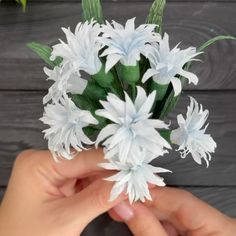 someone is holding some white flowers in their hand