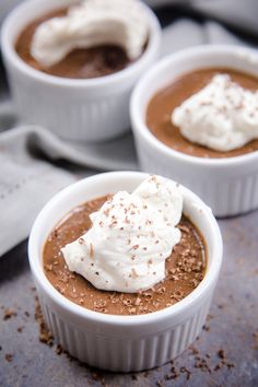 three small white bowls filled with chocolate pudding and whipped cream on top of each other