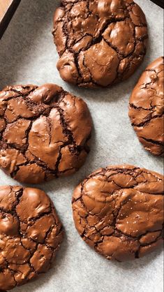 four chocolate cookies are on a baking sheet