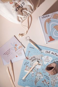 an assortment of children's books and knitting needles on a table with a drawstring bag