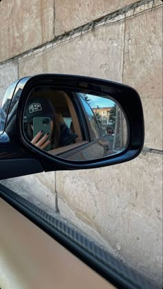 a side view mirror with a person taking a photo in the car's rear view mirror