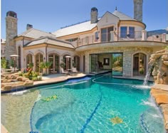 a large house with a pool in front of it and a waterfall coming out of the center