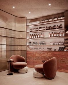 two chairs in front of a counter with bottles on the wall behind them and a table next to it