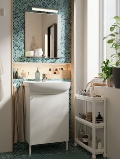 a white sink sitting under a bathroom mirror next to a green tiled counter top in front of a window