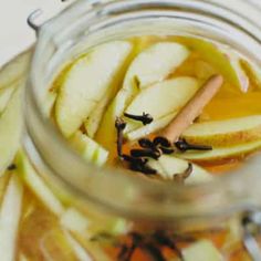 an apple cider is full of apples and cinnamon sticks in the jar with liquid