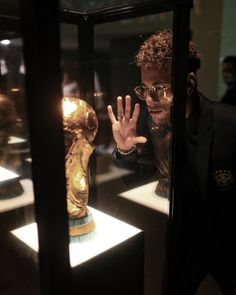 a man standing in front of a glass display case holding his hand up to the camera