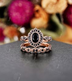 a black diamond ring sitting on top of a table next to some pink and white flowers