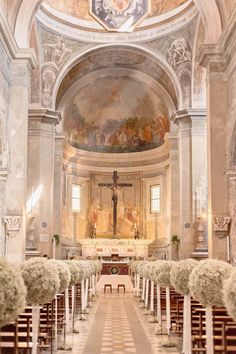 the interior of an old church with white flowers on the pews and paintings on the walls