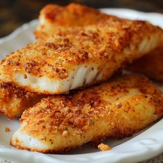 some fried fish on a white plate with parmesan sprinkles and seasoning