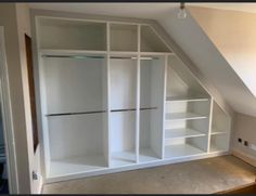 an attic bedroom with white closets and shelves