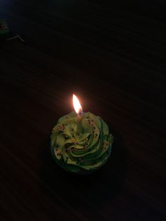 a cupcake with green frosting and a lit candle