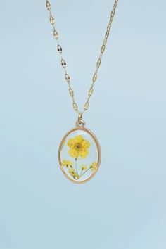 In Bloom Necklace from Gifts for Good's Ethical Jewelry Collection. Features dried yellow flowers encased in clear resin within a 14K gold plated setting. Adjustable 14k gold plated stainless steel chain. Hypoallergenic. Shop now for jewelry that gives back! Oval Pendant, Clear Resin, Yellow Flower, Delicate Flower, In Bloom