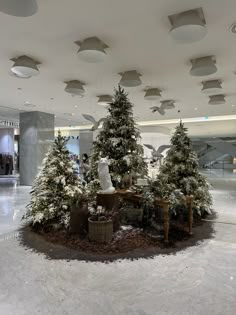 christmas trees in the middle of a lobby with people standing around them and snow on the ground