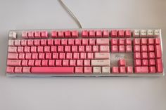 a computer keyboard with pink keys on it