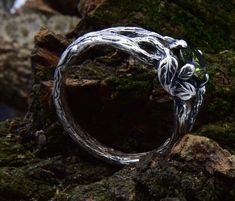 a silver ring sitting on top of a moss covered rock