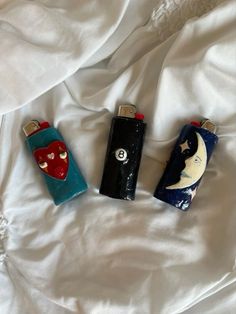 three lighters sitting on top of a white sheet