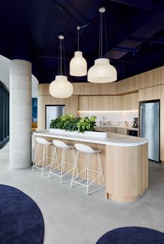 an open kitchen with white stools next to a bar and planters on the counter