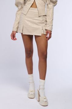 In a league of your own. The AKIRA Label Better Off Alone PU Houndstooth Skort In Ivory is part of a two-piece ensemble featuring a sleek faux leather composition, textured felt houndstooth patterning, a high rise waist, back pouch pockets, and an attached skirt overlay on the front with dual hem slits. Complete with a mini short silhouette from the back, rounded hems, a pull-on fit, and a tonal back zip closure. Amp up your look by styling with the coordinating AKIRA Label Better Off Alone PU Houndstooth Button Down Blouse In Ivory.  - Fabric: 50% Polyurethane 46% Polyester 2% Spandex, Lining: 100% Polyester - Some Stretch - Imported  (all measurements are approximate from size small) - 13” Waist to Hem  - Model is 5’8” Product ID: 395638  (all measurements are approximate from size 1X) - Better Off Alone, Ivory Fabric, Mini Short, Pocket Pouch, High Rise, Two Piece, Faux Leather, Sleek