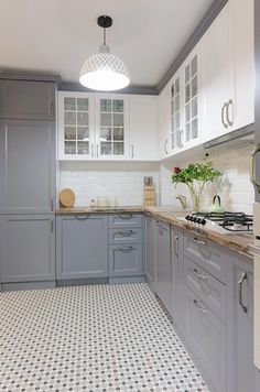 a kitchen with grey cabinets and white tile flooring