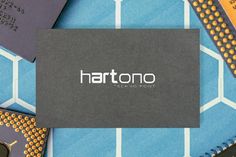 a black business card sitting on top of a blue and yellow table cloth with the word harttono printed on it