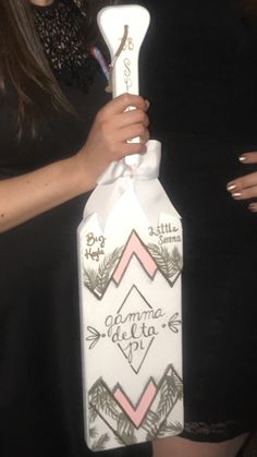 a woman is holding up a bottle shaped like a cross with an arrow on it