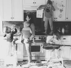 three children are playing in the kitchen with their mom